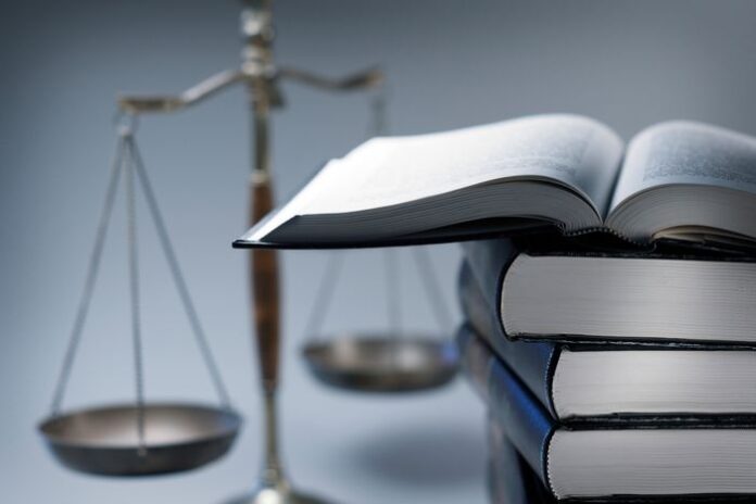 Stack Of Law Books In Front Of Scales Of Justice